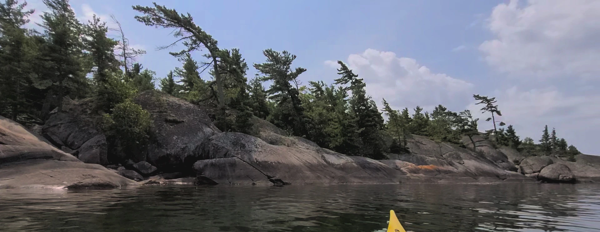 Western Shoreline of the Benjamind islands with red granite rock, white quartzite,
                trees and clear water